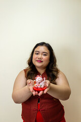 Woman holding lucky cat figurine, good fortune symbol, festive red outfit