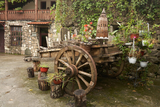 Using antique household items in street decor. A two-wheeled wooden Caucasian cart with plants in pots on the grounds of the Abbot Fortress in Gagra.
