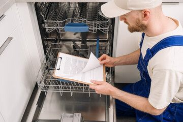Repairing a dishwasher in a modern kitchen during a routine maintenance service