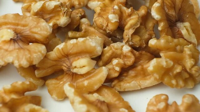 Scattering of walnut kernels on white background, macro slow motion.
