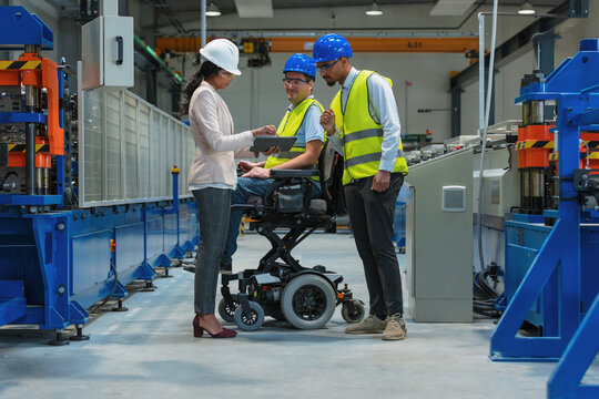 Female manager oversees production as workers with diverse backgrounds and disability collaborate in a factory setting focused on teamwork and inclusion. - Powered by Adobe