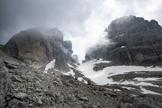 Cloudy rock peaks with glacial remnants of the Vedretta del Sfulmini and Bocca degli Armi, Brenta Mountains, Trentino, Italy