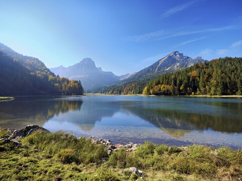 Autumn-colored forest is reflected in Obersee, N&auml;fels, Canton of Glarus, Switzerland