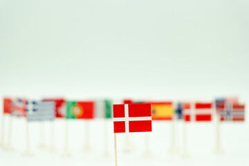 Flags of different countries with a focus on the Danish flag in a clear setting during the day