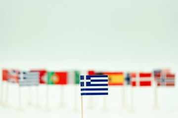 Small Greek flag among many flags from different countries on a light background in a display setting