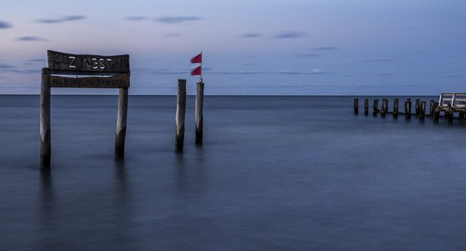 Wooden sign in the sea with inscription Zingst and Buhnen, long exposure, evening light, Zingst, Fischland-Dar&szlig;-Zingst, Western Pomerania National Park, Mecklenburg-Western Pomerania, Germany