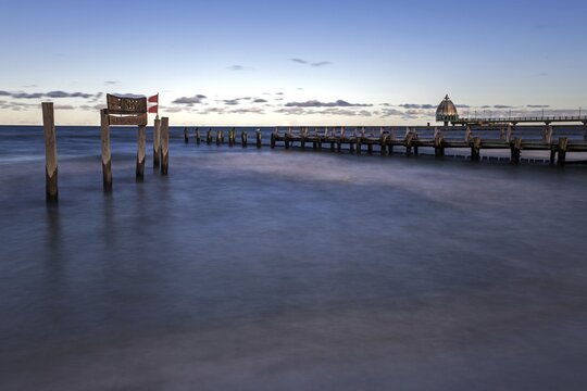 Wooden sign in the sea with inscription Zingst and wooden walkway, pier with diving gondola behind, panorama, long exposure, evening light, Zingst, Fischland-Dar&szlig;-Zingst, Western Pomerania Lagoon Area National Park, Mecklenburg-Western Pomerania, Germany