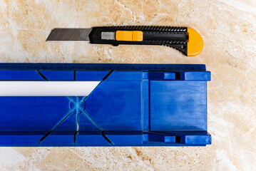 Cutting the corner of ceiling moldings from white polystyrene foam with a clerical knife using a...