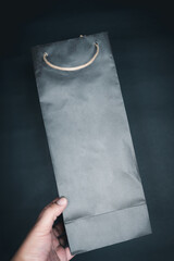 Hand holding black paper shopping bag retail purchase sale consumerism