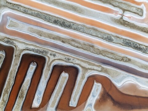 Saline ponds at the salt works near Chiclana de la Frontera. The orange-red colour depends on the level of salinity and is directly caused by the algae Dunaliella salina and brine shrimp. Aerial view. Drone shot. C&aacute;diz province, Andalusia, Spain