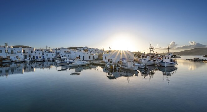 Fishing boats in the harbour of Naoussa at sunset, reflected in the sea, Sun star, White Cycladic houses, Naoussa, Paros, Cyclades, Greece