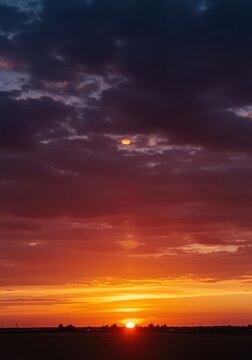 Espectacular puesta de sol con el horizonte encendido, presentando nubes esponjosas y vibrantes colores rojizos y anaranjados, sol, brillo, resplandor