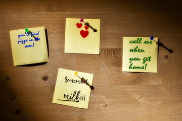 Four colorful sticky notes with handwritten messages and heart stickers, pinned to wood—capturing daily reminders and personal warmth.