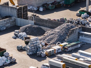 Aerial view of a scrap metal recycling facility with various piles of metal, debris, and materials in designated areas.