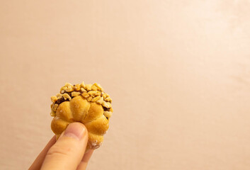 Sweet treat held by hand with chopped nuts on top in indoor setting unique dessert