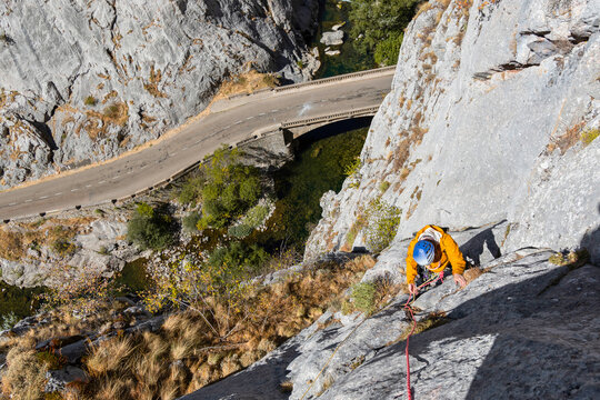 Climber Ascends Steep Rock Face with Scenic Road Below