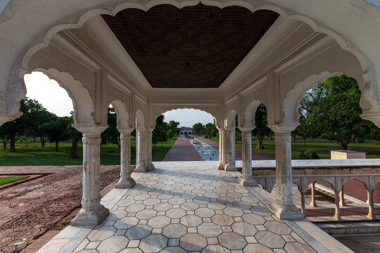 View of a marble pavilion framing a symmetrical garden path stretching into the distance, bordered by lush greenery, Lahore, Punjab, Pakistan.