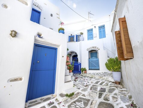 White Cycladic houses with blue doors and windows and flower pots, picturesque alleys of the village of Lefkes, Paros, Cyclades, Greece