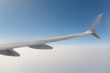 Airplane wing above the clouds in bright blue sky