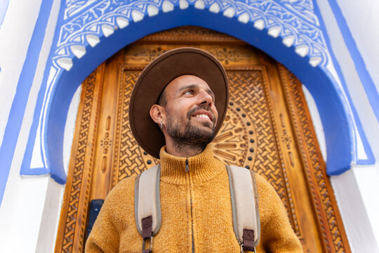 Smiling man by a decorative blue archway in Chefchaouen