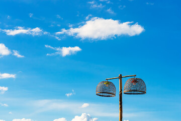 Lamps made from chicken coop with blue sky. Handmade bamboo lighting. Lamp holder from woven bamboo basket. Traditional handmade bamboo chicken coops repurposed as creative outdoor hanging lamps.