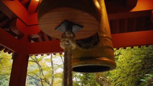 Person ringing a bell at a traditional japanese temple