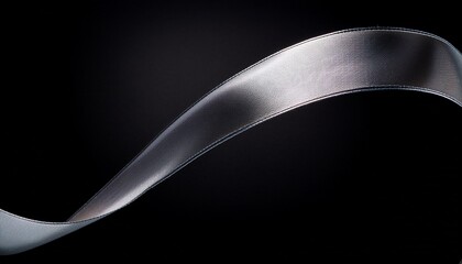 a thin silver metallic streamer or ribbon swirls vertically in a gentle elegant curve against a black backdrop