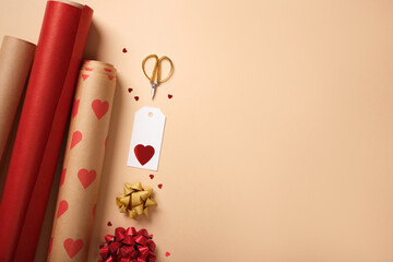 Gift wrapping background with red paper rolls, ribbon, scissors, tag and hearts. Copyspace.