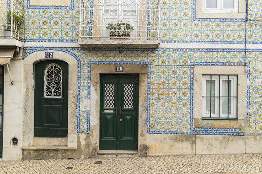 View of the building's facade with vibrant blue and yellow patterned tiles, complemented by dark green doors, Lisbon, Lisbon, Portugal.