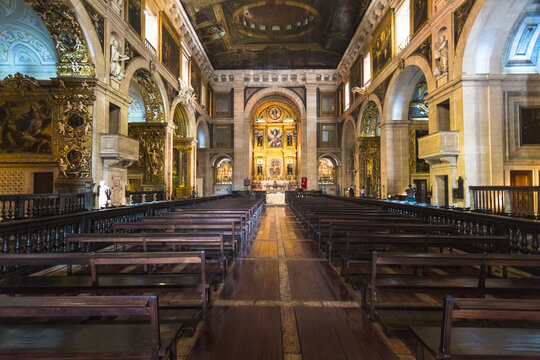 View of the grandeur of the Igreja de S&Atilde;&pound;o Roque, with its ornate gold carvings, dark wooden pews, and towering arches, bathed in a soft, reverent light, Lisbon, Lisbon, Portugal.