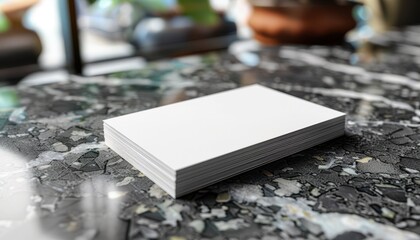 Stack of blank white business cards on a marble surface in a blurred background