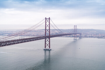 View of the Ponte 25 de Abril bridge stretching across the tranquil Tagus River under a muted sky, a blend of steel and water, Lisbon, Lisbon, Portugal.
