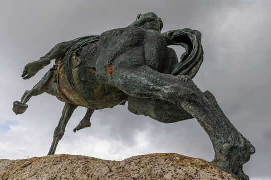 View of a bronze equestrian statue on a rocky base set against a cloudy sky, captured from a low angle emphasizing its size, Cape Town, Western Cape, South Africa.