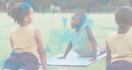 Stretching three children doing cobra backbend on light mat at grass field, wearing yellow pinnie