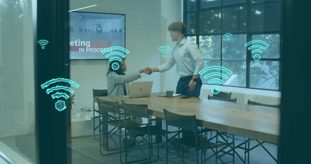 Shaking hands woman in blazer and man in shirt at office table with laptop Wi-Fi graphics