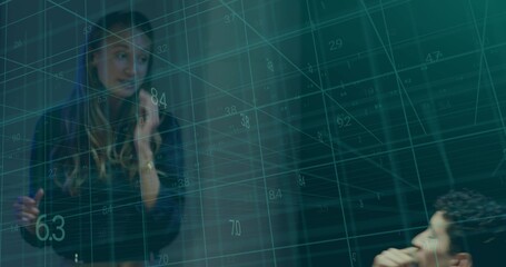 Presenting mid adult woman pointing at teal 3D data grid in office meeting, wearing dark blazer