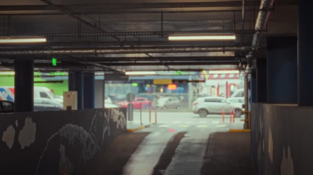 A city road is visible from an underground garage, with a ramp leading to the gated parking area, featuring marked parking spaces and a parking meter, near the floor exit