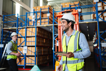 Professional warehouse workers using digital tablet with forklift and pallets. Logistics team management, inventory control, and industrial supply chain concept.