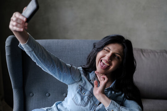 Woman sitting in a chair pulling funny faces and taking a selfie