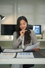 Businesswoman analyzes expenses using tablet and paper. Person in suit calculates costs, income,...