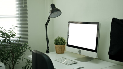 Minimal home office desk with computer and blank screen for mockup or workspace design