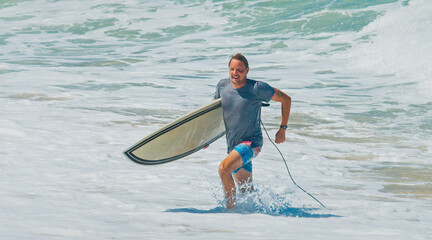 Young surfer walk with surfing boards on the beach in Brazil