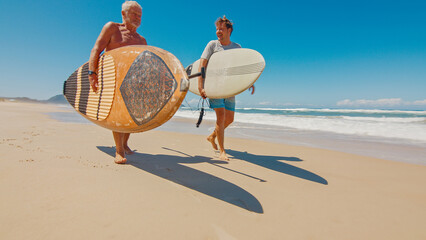 Young and elderly surfers walk with surfing boards on the beach in Brazil