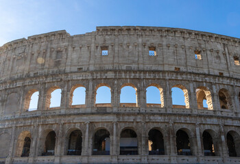 Obraz premium Famous Coliseum in Rome. Colosseum, or Coliseum. Part of the wall of an antique stone structure with arches. Italy, Europe. Famous touristic place in the world, Europe. Beautiful blue sky background.
