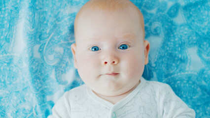 Portrait of the newborn boy (3 months old) with deep blue eyes in the bright white room