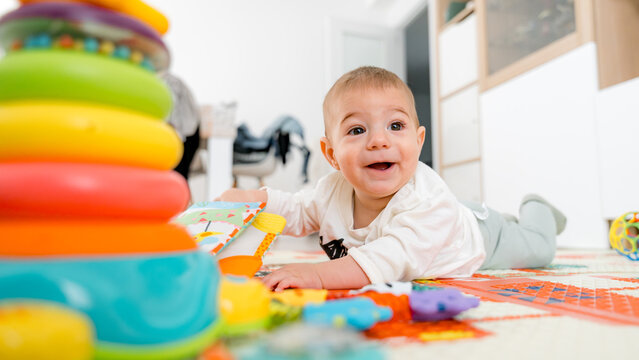 Happy baby playing on colorful playmat with toys