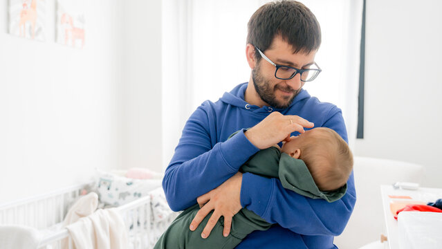 Father gently cradling baby in nursery setting