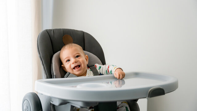 Happy baby in a high chair enjoying breakfast time