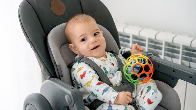 Baby smiling in seat while playing with toy ball
