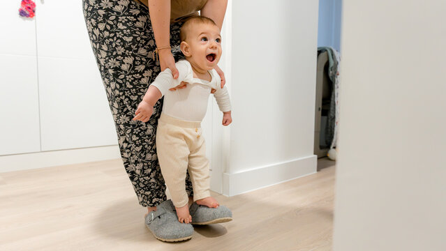 Baby standing with mother in cozy home environment